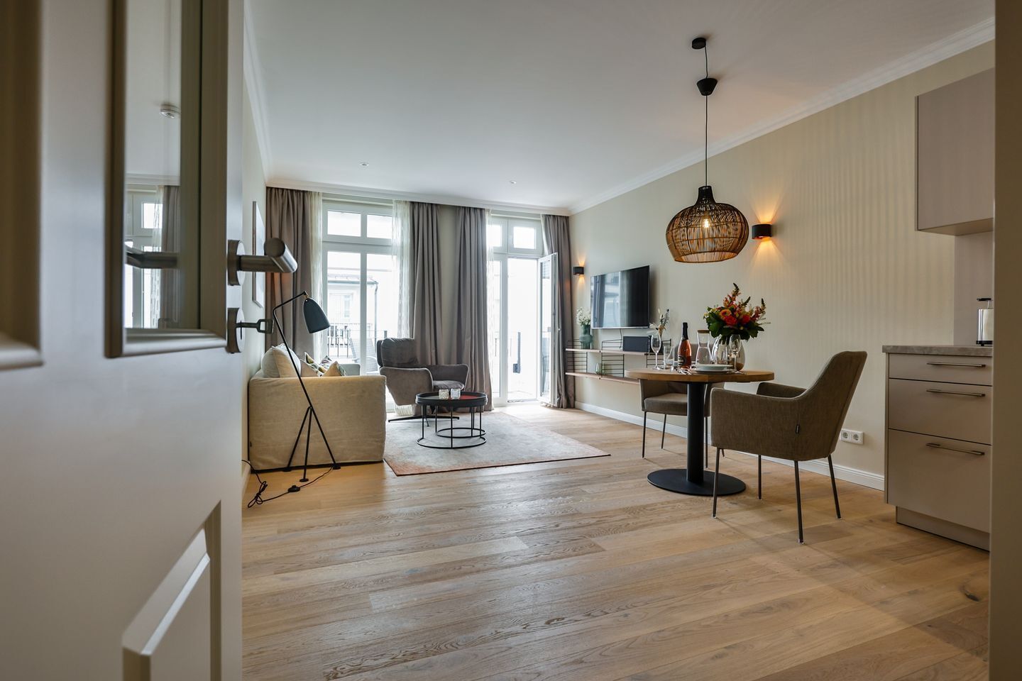 A modern living room with a sofa, chairs, a dining table, and a TV.