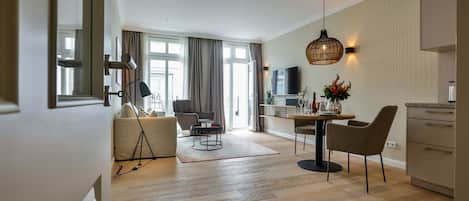 A modern living room with a sofa, chairs, a dining table, and a TV.