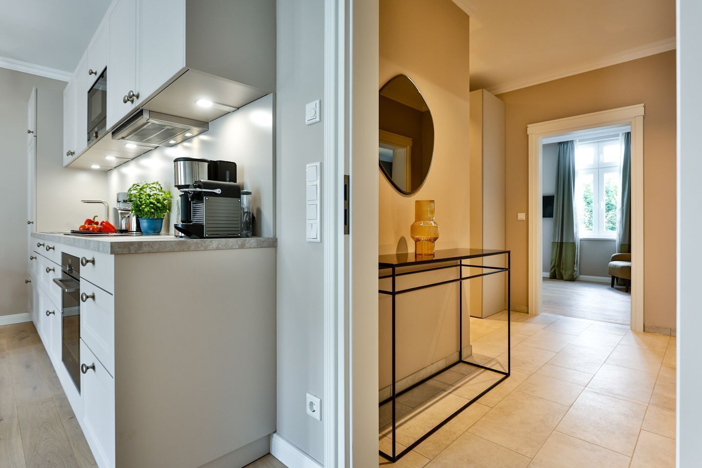 A modern kitchen with white cabinetry, a built-in stove, and a coffee machine.