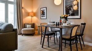 Un comedor con una mesa dispuesta para cuatro personas, un sofá, una lámpara y cuadros en la pared.