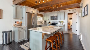 Una cucina moderna con una grande isola, elettrodomestici in acciaio inossidabile e un soffitto in legno.