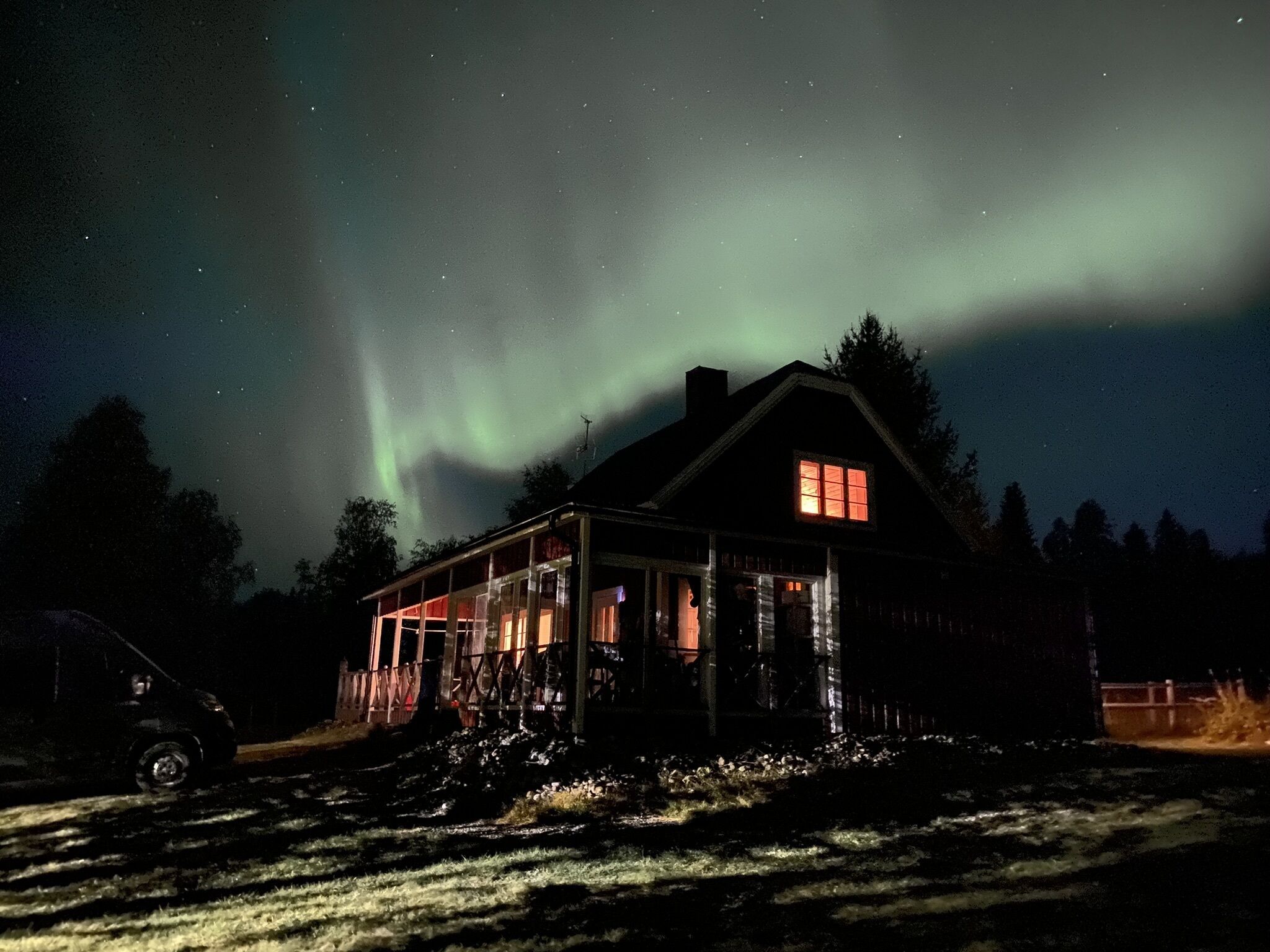 A house with a visible window and a car parked outside at night.