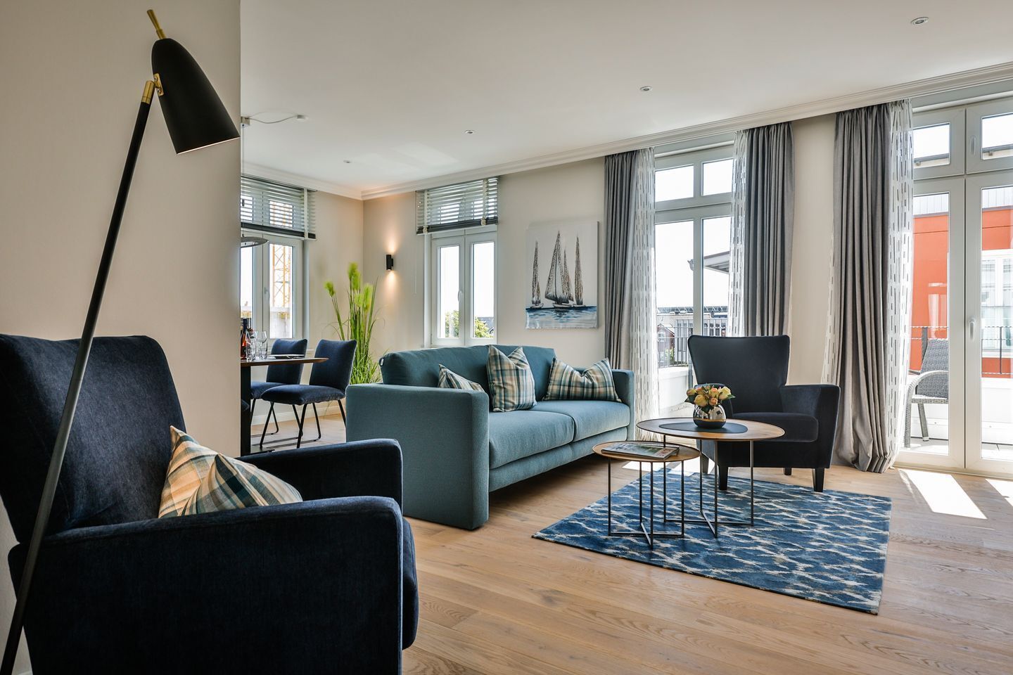 A modern living room with a sofa, two armchairs, a coffee table, and a floor lamp.