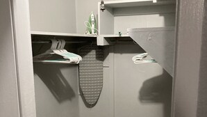 Zona de bugaderia petita i tancada amb una estendal, un ferre i una taula de planxar amb dibuixos.