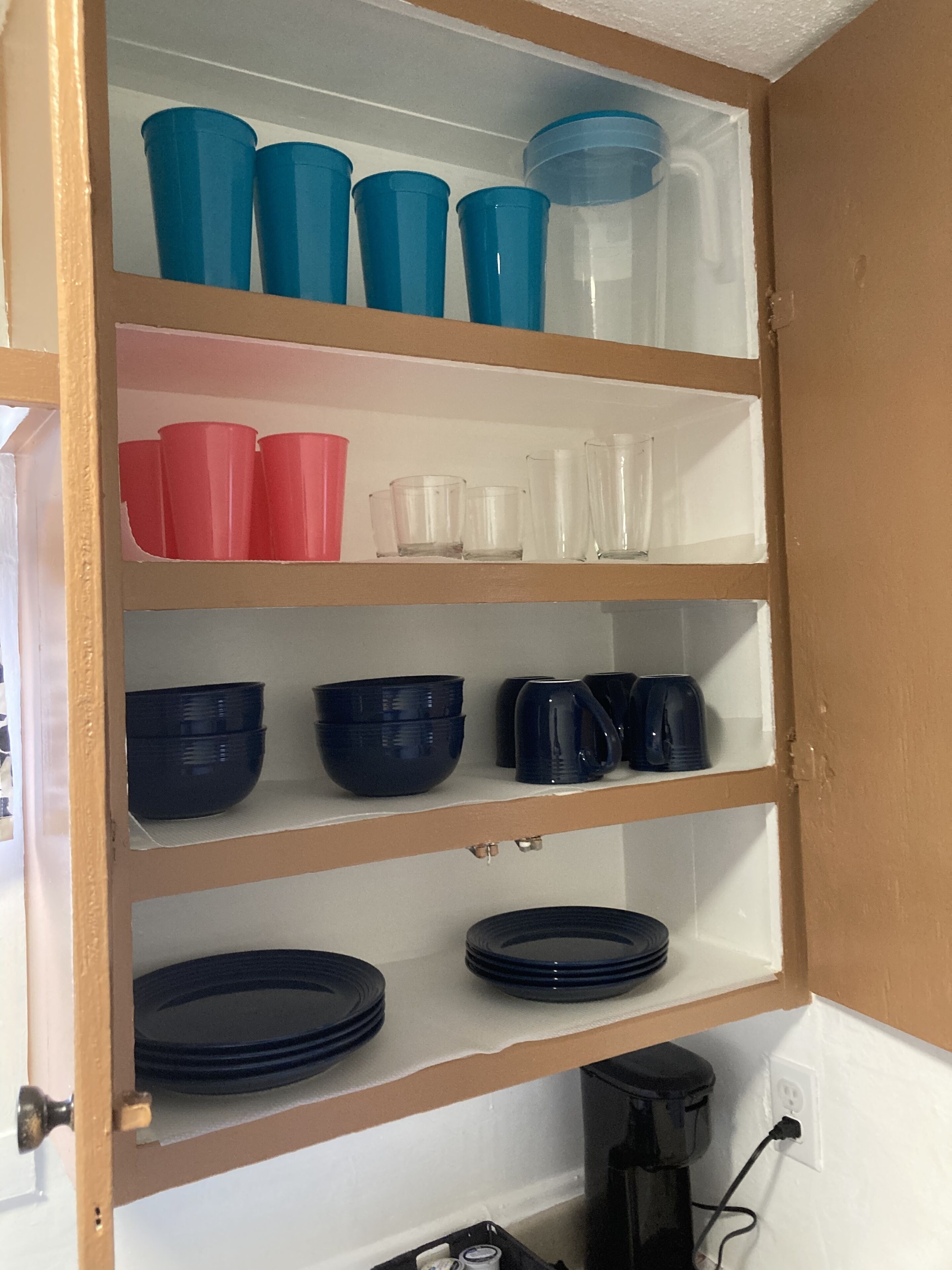 A kitchen cabinet with shelves containing various kitchenware items.