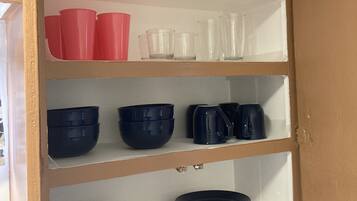 A kitchen cabinet with shelves containing various kitchenware items.