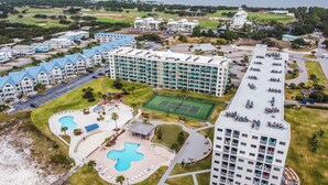 Een resort met meerdere gebouwen, een tennisbaan en een zwembad.