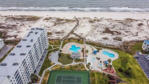 A coastal hotel with a swimming pool, tennis court, and beach access.