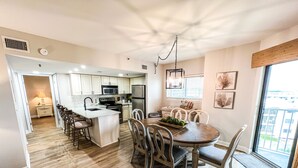 Een moderne keuken met witte kasten, een centraal eiland en een eethoek met een houten tafel en stoelen.