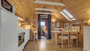 Une cuisine compacte dotée d’appareils électroménagers modernes, un coin repas avec des meubles en bois et un espace nuit confortable offrant une vue par la fenêtre.