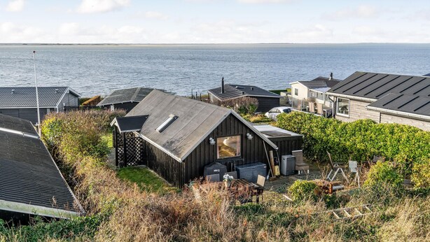 Une propriété située sur la côte, avec une maison imposante dotée d’un toit en pente et d’une petite terrasse.