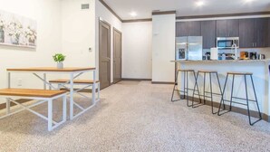 A modern kitchen with a central island, bar stools, and a dining table with benches. - Boulevard Stays Charming 2BR, Parking (Middletown)