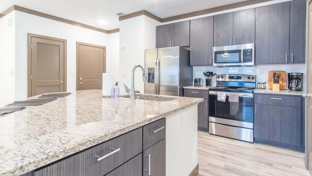 A modern kitchen with granite countertops, stainless steel appliances, and dark wood cabinets. - Boulevard Stays Charming 2BR, Parking (Middletown)