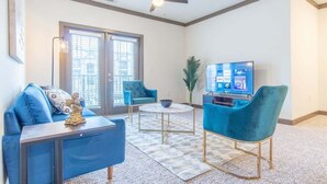 A modern living room with a blue sofa, two blue armchairs, a coffee table, a television, and a ceiling fan. - Boulevard Stays Charming 2BR, Parking (Middletown)