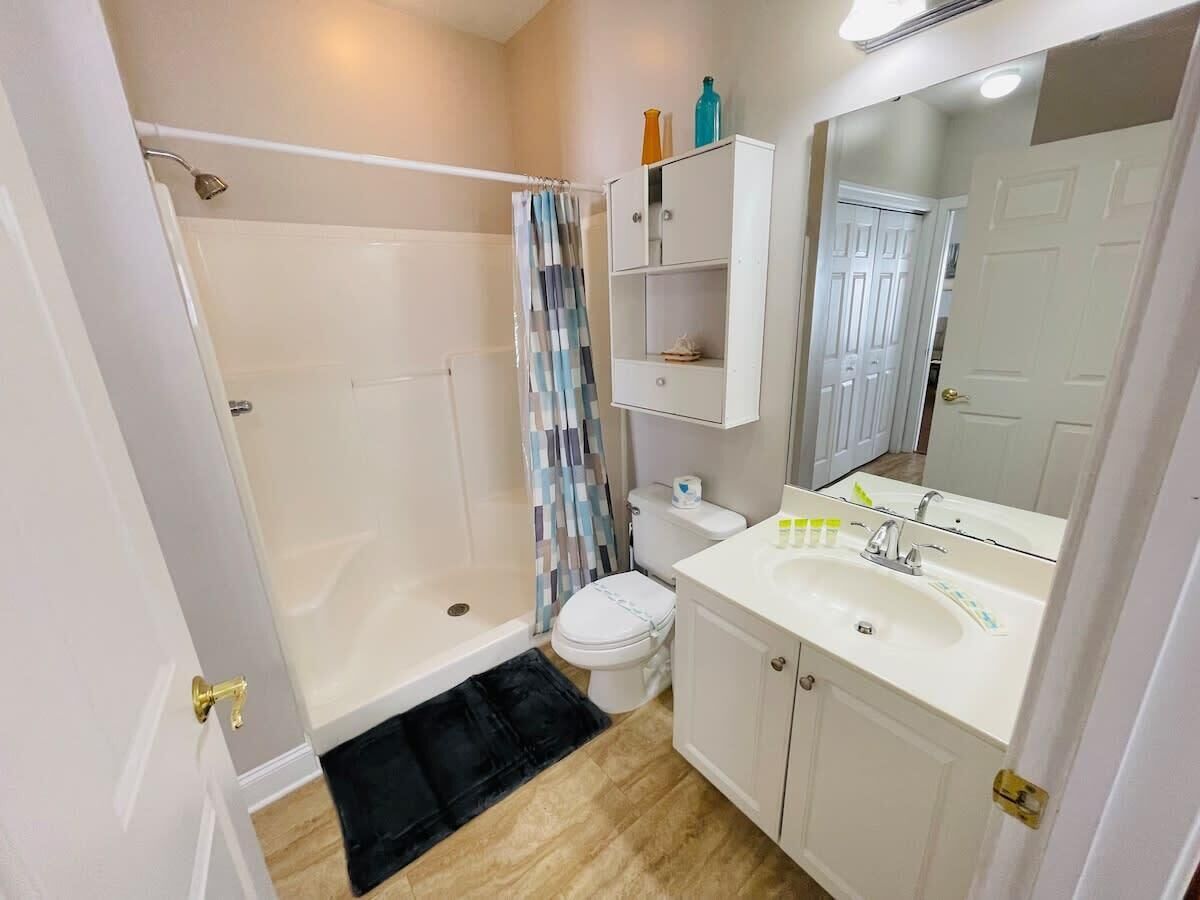 Une salle de bain équipée d’une douche, de toilettes, d’un lavabo et d’un miroir.