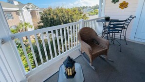 Un balcon abrité, avec un fauteuil en osier, une petite table et une lanterne.