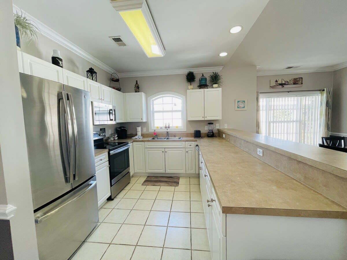 A modern kitchen with white cabinets, stainless steel appliances, and a beige countertop.
