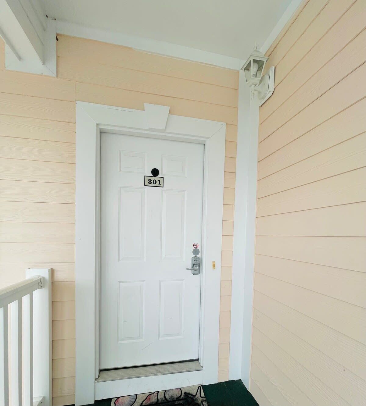 A white door with the number 301, a mailbox, and a small step leading to the entrance.
