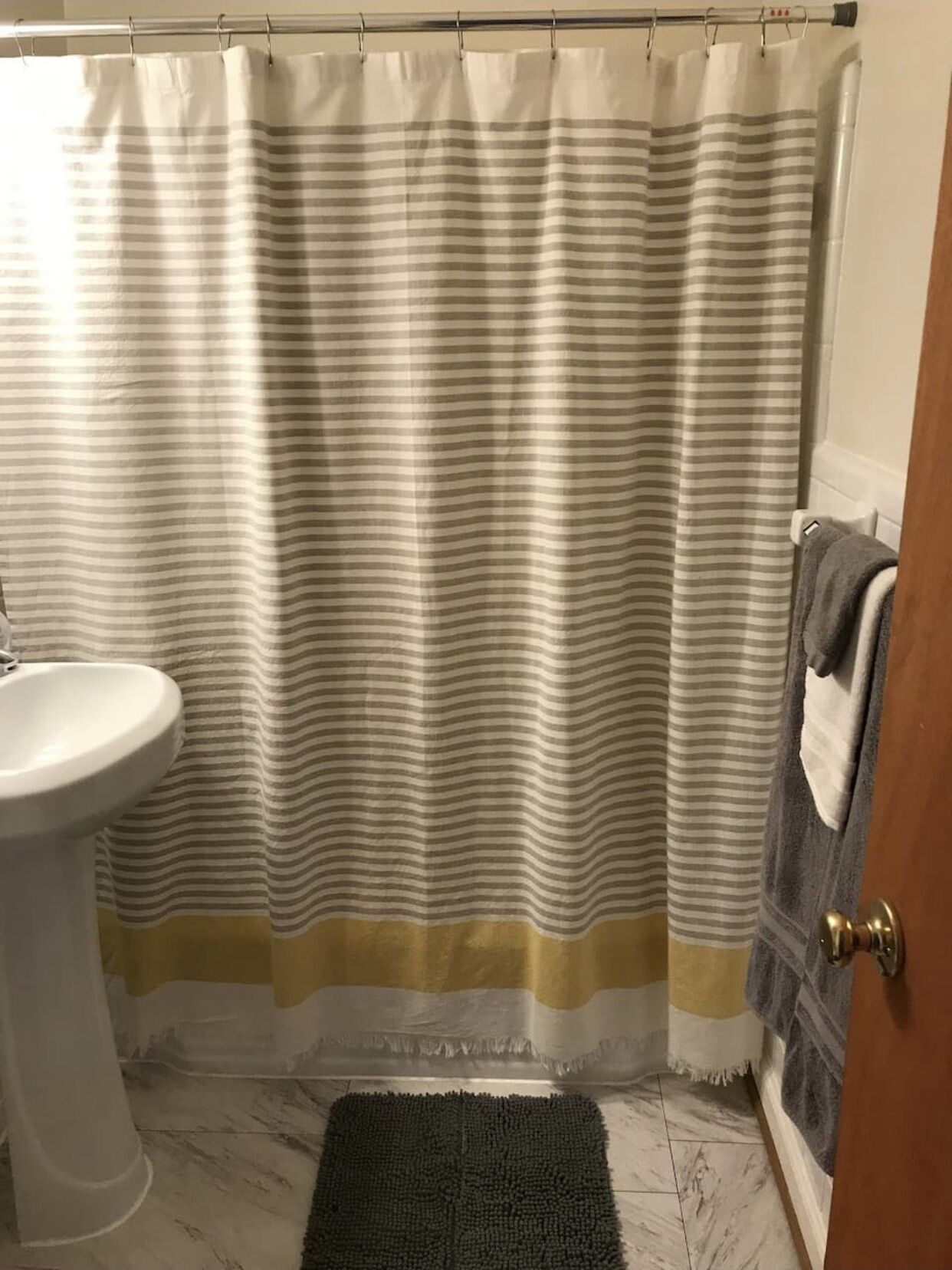 A bathroom with a striped shower curtain, a sink, and a towel rack.