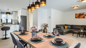 A modern dining area with a wooden table set for six, surrounded by chairs. There are hanging pendant lights above the table. - Amazing home in Galizana (Galizana)