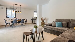 A modern living room with a sofa, a coffee table, and a dining area with chairs and a table. - Amazing home in Galizana (Galizana)