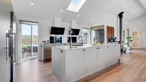 A modern kitchen with a large island, built-in appliances, and a skylight.