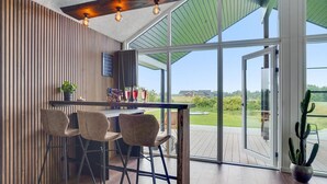A modern bar area with wooden paneling, a glass partition, and a view of the outdoors.