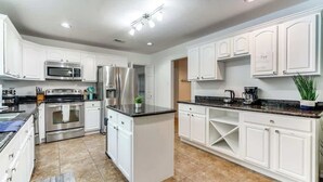 Une cuisine moderne avec des meubles blancs, des appareils en acier inoxydable et un îlot central.
