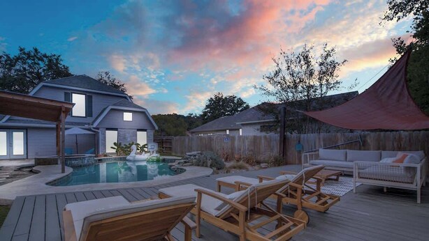 Un jardin avec une terrasse en bois, des chaises longues, une piscine et un espace salon abrité.