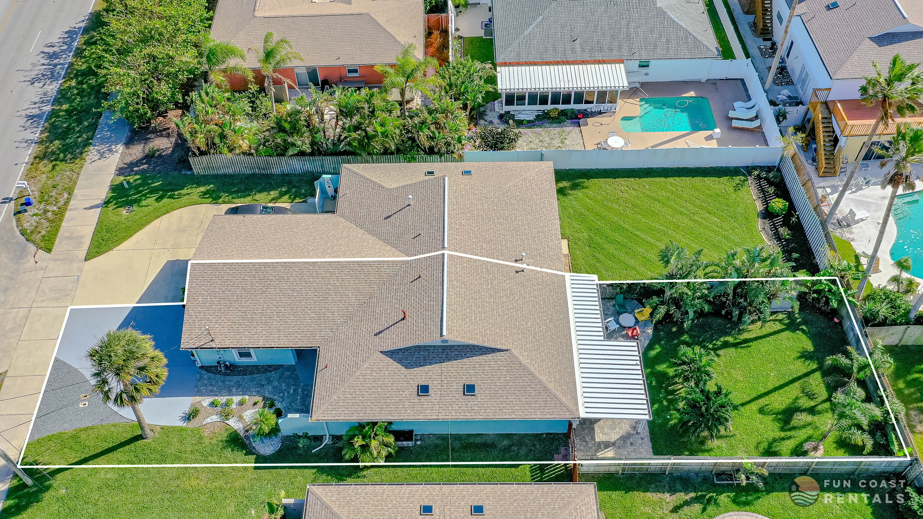 Luchtfoto van een woonwijk met een huis, gekenmerkt door een groot, schuin dak, een zwembad en een verzorgd gazon.