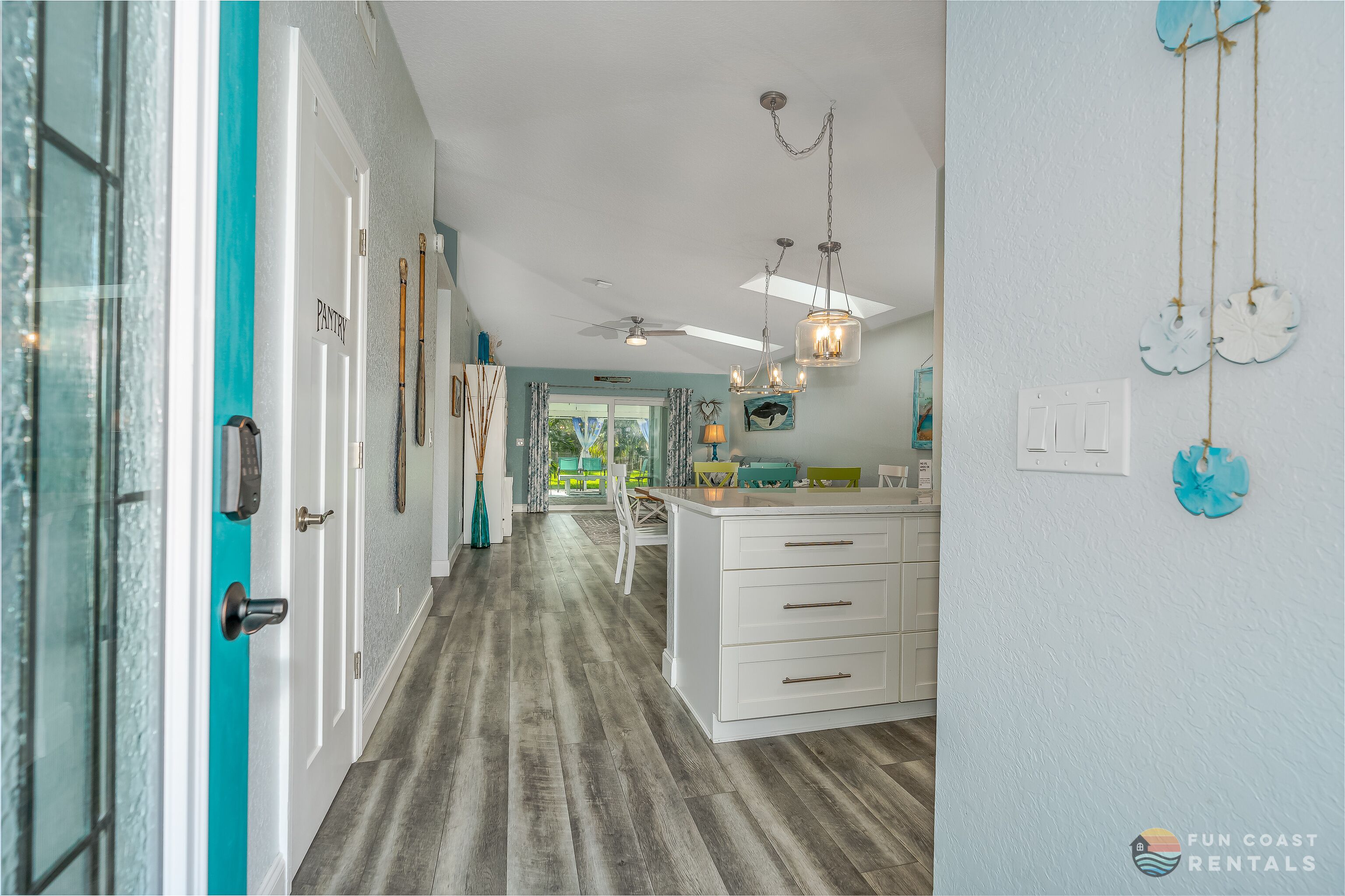 A hallway with a white door, a ceiling fan, and a chandelier.