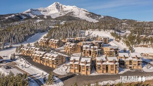 A snow-covered mountain with a ski resort in the foreground. - Steps to the Gondola | Ski-In/Ski-Out Luxury Penthouse (Big Sky)