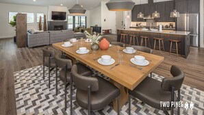 A modern kitchen with dark cabinetry, a central island with stools, and pendant lighting. - Steps to the Gondola | Ski-In/Ski-Out Luxury Penthouse (Big Sky)