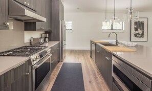 Une cuisine moderne avec des appareils en acier inoxydable, un plan de travail en bois et un tapis noir.