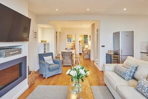 A modern living room with a sofa, armchair, and a TV mounted on the wall.