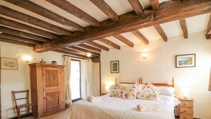 A bedroom with a wooden bed frame, a wooden wardrobe, and a nightstand with a lamp.