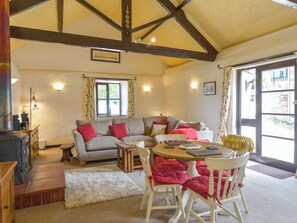 A cozy living room with a sofa, chairs, a small table, and a fireplace. - Pillhead Cider House (Bideford)