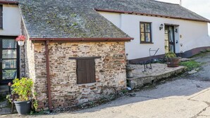 A stone building with a tiled roof, a small window, and a door.