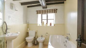 A bathroom with a toilet, bidet, sink, and bathtub.