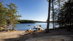 A lakeside campsite with a dock, chairs, and boats.