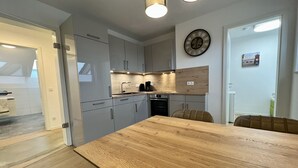 Uma cozinha moderna com armários cinza, uma mesa de jantar de madeira e um relógio na parede.