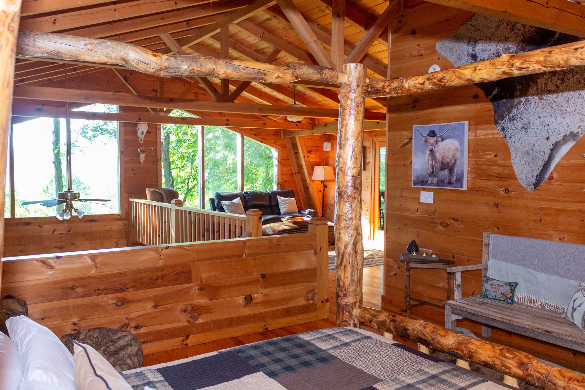 A cozy cabin with a loft bedroom, a wooden deck, and a large window overlooking the forest.