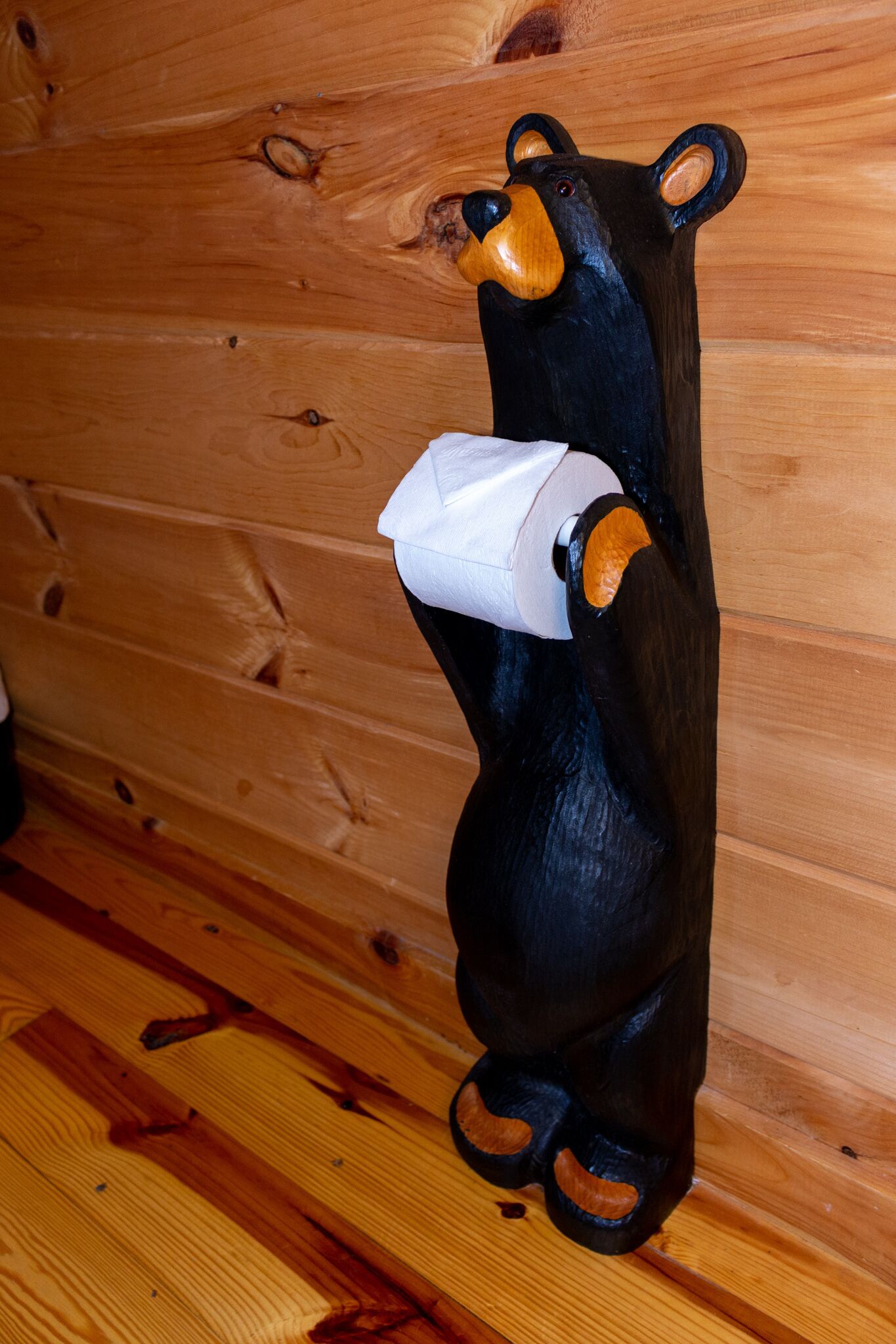 A wooden bear sculpture holding a tissue.