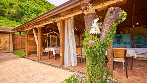 A rustic wooden building with a covered outdoor dining area, stone pathway, and a decorative tree with ivy. - 2 bedroom pet friendly home in Hrastovica (Hrastovica)