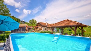 A swimming pool with a wooden deck and a gazebo, surrounded by houses and greenery. - 2 bedroom pet friendly home in Hrastovica (Hrastovica)
