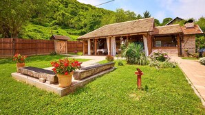 A rustic house with a covered patio, a fenced backyard, and a lush green lawn. - 2 bedroom pet friendly home in Hrastovica (Hrastovica)