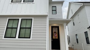 A two-story residential building with a black front door, a small porch, and a visible address number. - Oxford Townhouse Minutes from campus! (Oxford)