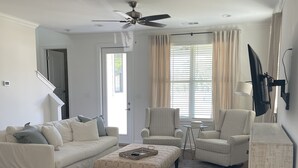A living room with a sofa, two armchairs, a coffee table, a TV mounted on the wall, and a ceiling fan. - Oxford Townhouse Minutes from campus! (Oxford)