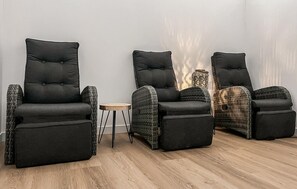 Une pièce avec trois fauteuils noirs et une petite table ronde.