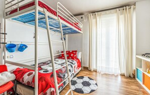 Ein Schlafraum mit Etagenbetten, einer Bettdecke mit Fußballmuster, einem Teppich mit Fußballmotiv und einem Fenster mit Vorhängen.